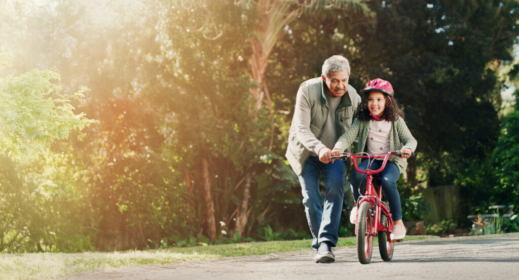 A grandfather teaching his grandaughter to ride a bike to represent grandparent visitation rights